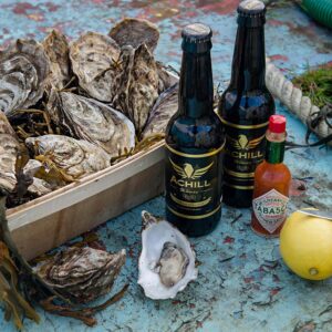 Gift box with Achill brewery beer, shucked oyster, lemon and tobasco sauce on the sole of the boat